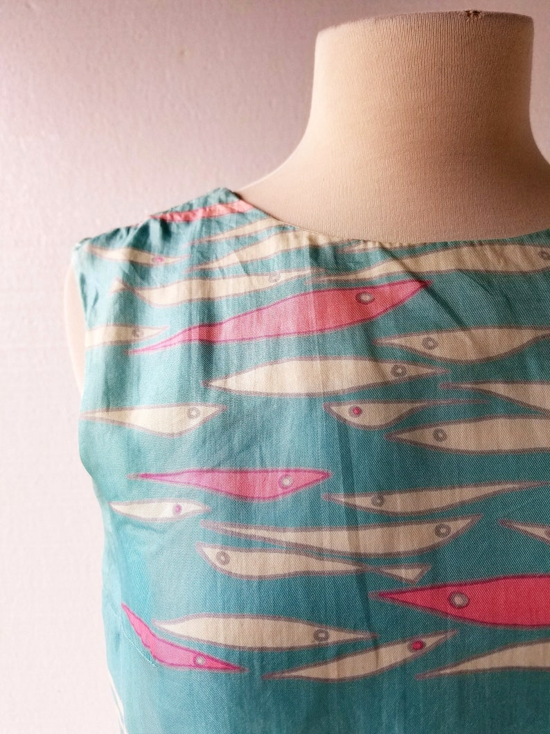 May include: A sleeveless dress with a turquoise background and a pattern of white and pink fish.