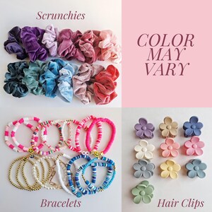 May include: Assortment of colourful hair accessories, including velvet scrunchies, beaded bracelets, and flower-shaped hair clips. The text "COLOR MAY VARY" is displayed on a pink background.