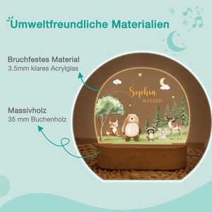 May include: A wooden night light with a forest scene featuring a fox on a swing, a bear, a raccoon, a rabbit, and a deer. The light is personalized with the name "Sophia" and the date 14.02.2025. The base is made of 35 mm beech wood.