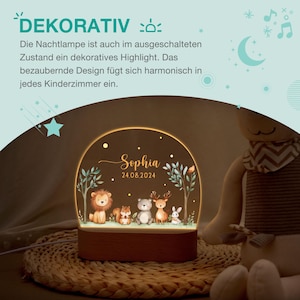 Pode incluir: Uma luz noturna com base de madeira e um brilho quente, apresentando uma cena da floresta com um le&atilde;o, um esquilo, um urso, um veado e um coelho. O nome "Sophia" e a data 24.08.2024 s&atilde;o exibidos. O texto "DEKORATIV" est&aacute; no topo.