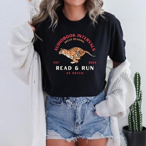 Può includere: Maglietta nera con un'immagine di una tigre che corre e il testo "Audiobook Intervals Speed Reading Est 2024 Read & Run 2x Speed"