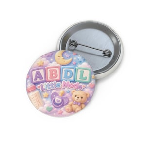 May include: A round pinback button featuring a pastel-colored design with the text ABDL Little Mode, a baby bottle, a pacifier, a teddy bear, a crescent moon, and stars against a background of soft clouds, with a metal pin mechanism on the back.