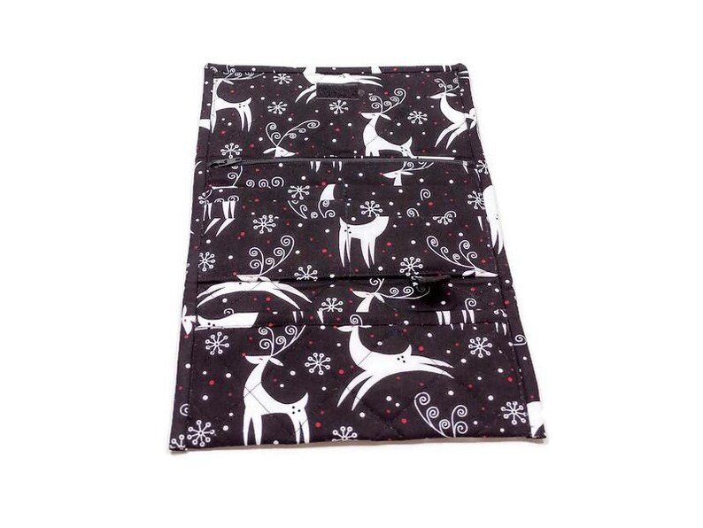 May include: Black fabric wallet with a white reindeer and snowflake pattern. The wallet has multiple compartments and a zipper closure. The design includes red accents and a quilted texture, suggesting a holiday theme.