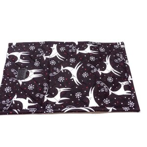 May include: A black quilted fabric item with a white reindeer and snowflake pattern. The reindeer are leaping, and the snowflakes are small and white. The item has a small black velcro closure.