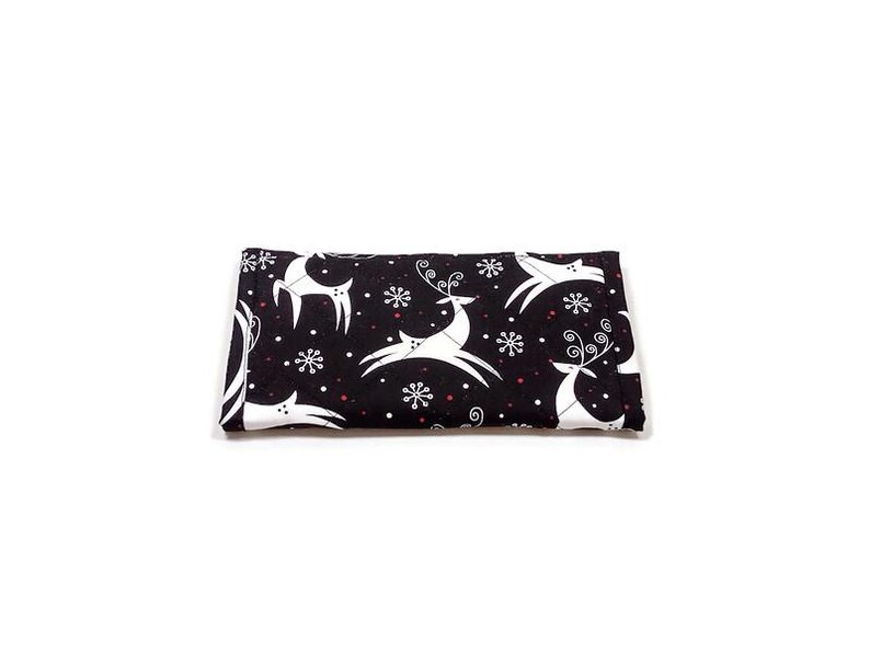 May include: A folded black fabric item with a white reindeer and snowflake pattern. The reindeer are stylized with curved lines, and the snowflakes have six points. Small red dots are scattered throughout the design.