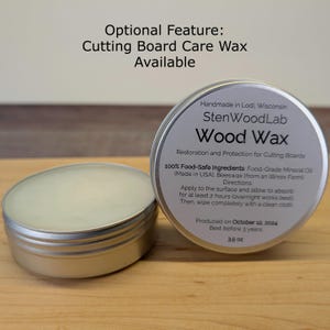 Op de afbeelding: Twee kleine, zilveren blikken StenWoodLab Wood Wax voor snijplanken. E&eacute;n blik is open en onthult een romige was. Het etiket vermeldt dat de was is gemaakt met voedselveilige ingredi&euml;nten en geproduceerd op 12 oktober 2024. Het nettogewicht is 99 g.