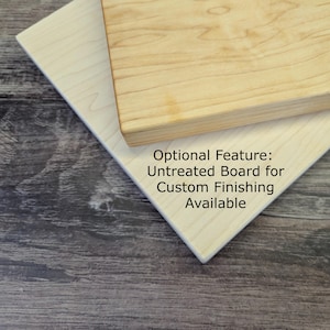 Op de afbeelding: Twee onbehandelde houten planken, &eacute;&eacute;n lichtgekleurd en de andere een middentint, worden onder een hoek weergegeven. De tekst "Optional Feature: Untreated Board for Custom Finishing Available" is zichtbaar. De planken zijn waarschijnlijk voor knutsel- of houtbewerkingsprojecten.