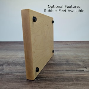Op de afbeelding: Een lichtgekleurde houten snijplank met afgeronde hoeken. De plank heeft zwarte rubberen voetjes aan de onderkant. De tekst "Optional Feature: Rubber Feet Available" is zichtbaar. De houtnerf is zichtbaar.