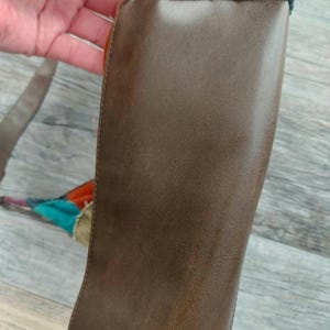 May include: A brown leather bag with a patchwork design of corduroy fabric in various colors, including beige, brown, and green.