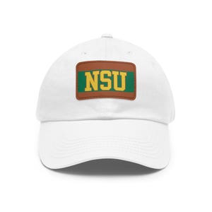 Op de afbeelding: Een witte baseballpet met een gebogen klep. De pet heeft een bruin rechthoekig embleem met de letters "NSU" in geel, tegen een groene achtergrond. Een klassiek, casual accessoire.