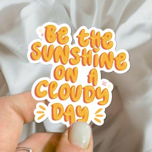 Sticker inspirant "Be the sunshine on a cloudy day" – Citation positive et lumineuse pour glow up