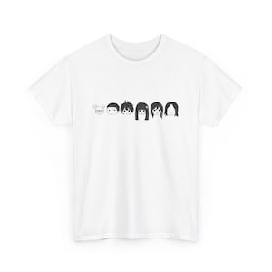 May include: White t-shirt with a black ink illustration of six cartoon faces. The faces are drawn in a variety of styles, showing different hairstyles and expressions. The design is positioned centrally on the shirt.
