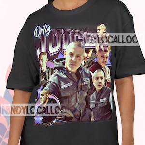 Peut inclure: T-shirt noir avec un collage d'images d'un homme et le texte "Ortiz Juice". L'homme porte une veste et un gilet en cuir. Le t-shirt a un design vintage, de style rétro.