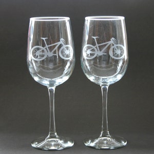 Pu&ograve; includere: Due bicchieri da vino in vetro trasparente con disegni di mountain bike incisi.