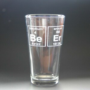 May include: A clear glass pint glass with the chemical symbols for Beryllium (Be) and Erbium (Er) etched on the front. The symbols are in a white color and include the atomic number and atomic weight for each element.
