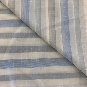 Puede incluir: Tela blanca con rayas azules. La tela tiene una textura sutil y una apariencia ligeramente transparente.