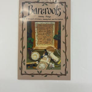 May include: A brown pamphlet with a green vine border. The title is "Bareroots Sewing Things #88 Quilt Stitchery, Sewing Roll, and Pin Cushion". The cover features a framed cross-stitch design with the words "cotton flannel wool measure cut pin sew appliqué press baste quilt bind and struggle".