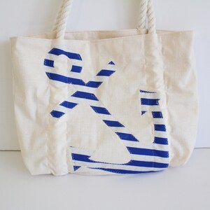 May include: A white canvas tote bag with a blue and white striped anchor design.