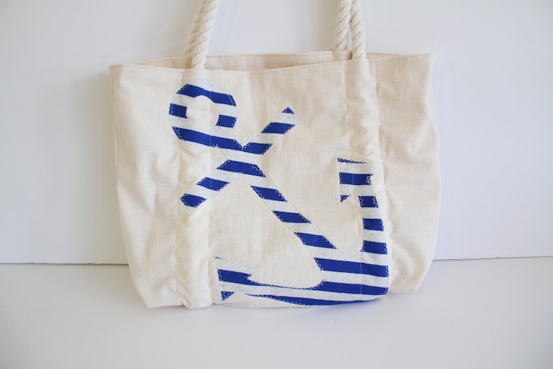 May include: A white canvas tote bag with a blue and white striped anchor design.