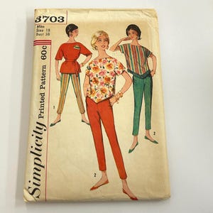 May include: A vintage Simplicity sewing pattern envelope 3703 for Miss size 18, bust 38. The cover features illustrations of three outfits including a floral top with orange pants, a solid orange top with striped pants, and a striped top with green pants.