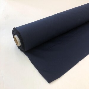 May include: A roll of dark blue fabric. The fabric is rolled up and the end is folded over.