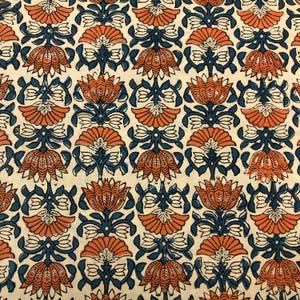 Pode incluir: Um tecido branco com um padrão repetitivo de flores estilizadas laranja e azul. As flores são dispostas em um padrão simétrico e têm um design tradicional indiano.