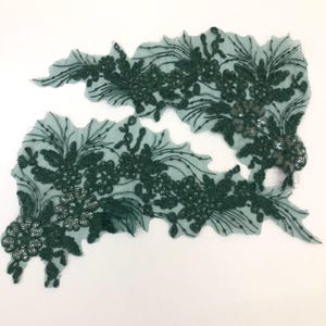 May include: Two pieces of green lace trim with sequins. The lace is in a floral pattern.