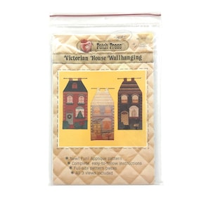 May include: A package featuring a Victorian House Wallhanging applique pattern. The pattern showcases three colourful house designs. The package includes the text "Patch Press" and details about the pattern, such as "New! Fun! Applique pattern" and "All 3 views included."