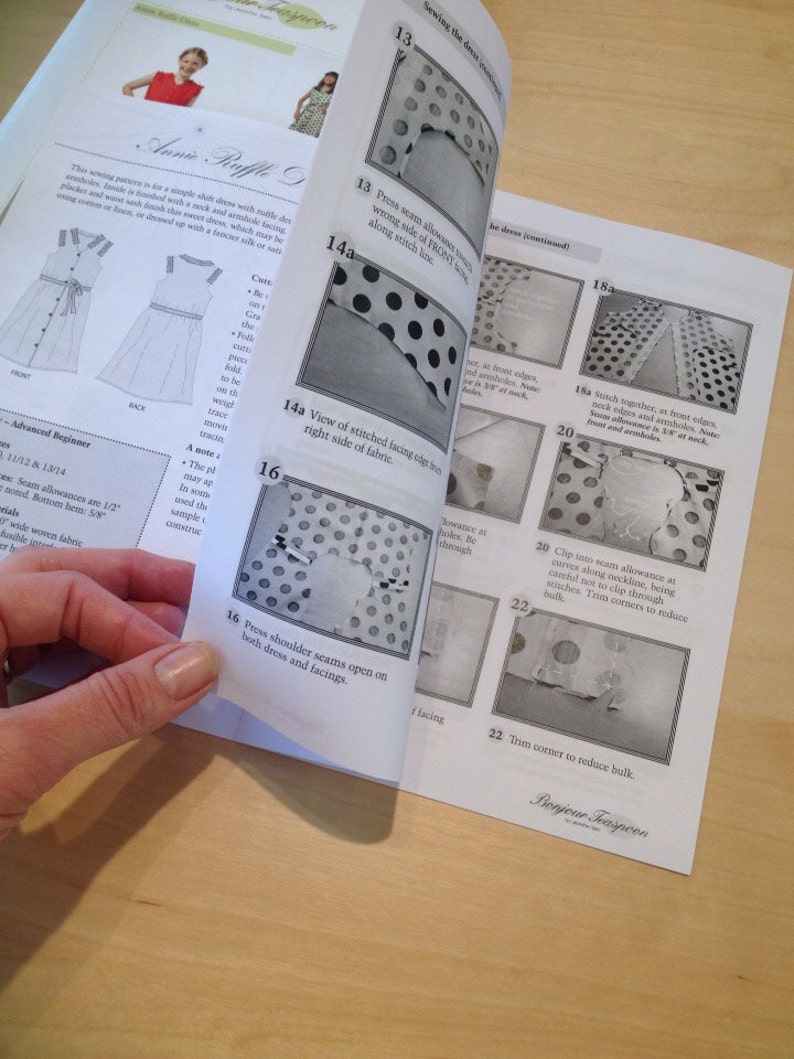 May include: A close-up of a sewing pattern instruction booklet for a dress with a polka dot pattern. The instructions include steps for pressing seams, stitching together fabric pieces, and trimming corners to reduce bulk.