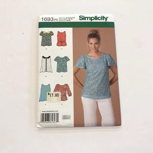 Può includere: Un cartamodello Simplicity per top, con cinque stili diversi. Il cartamodello include un top in pizzo blu a maniche corte, un top rosso a maniche lunghe, un top blu a maniche corte, un top bianco con colletto nero e un top bianco con colletto nero. Il cartamodello è numerato 1693 P5 e costa 17,95 €.