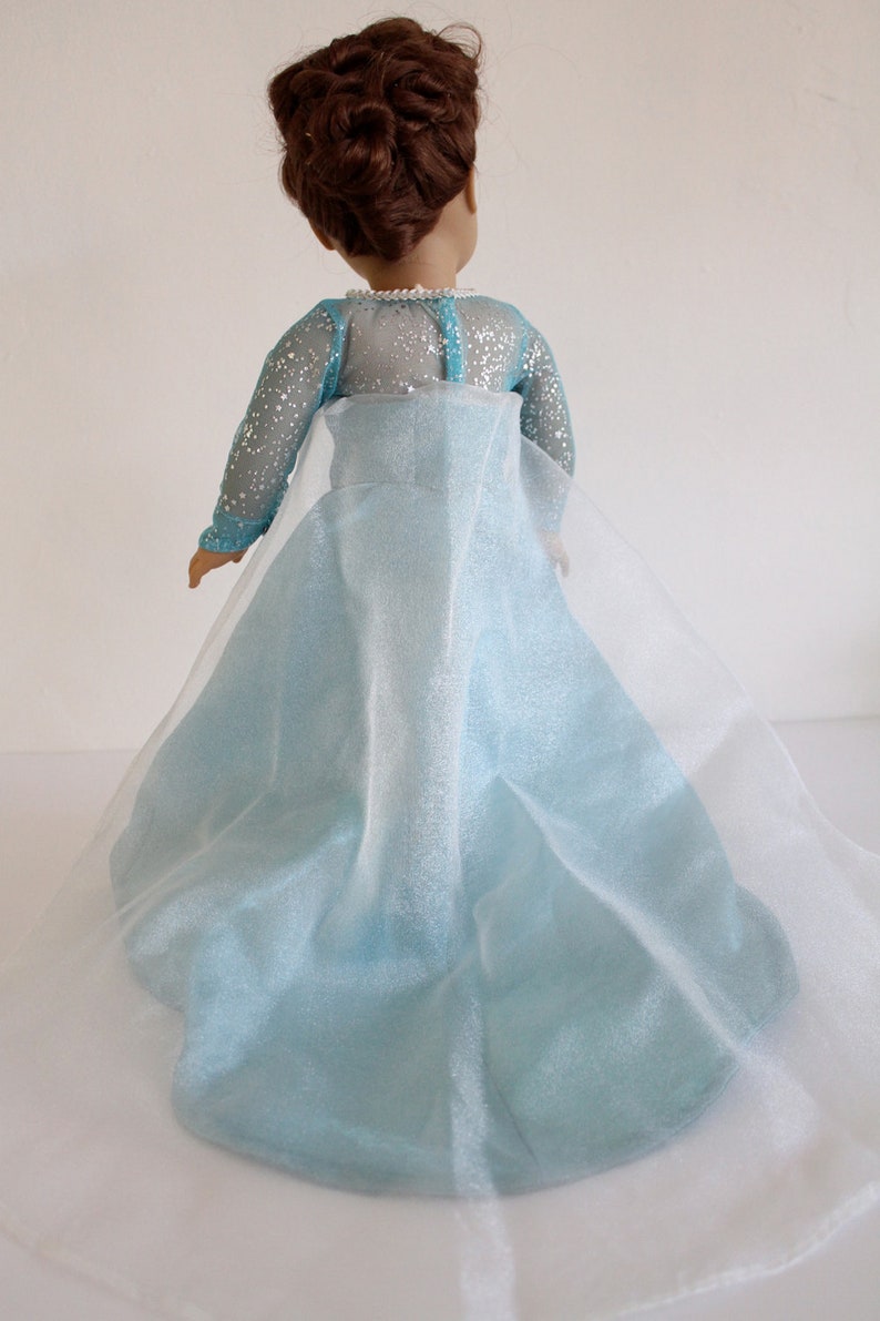 May include: A light blue dress with a sheer overlay. The dress has a sparkly bodice and a flowing skirt.