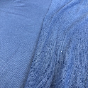 Pode incluir: Close-up de duas peças de tecido azul, uma com textura lisa e a outra com textura de malha.