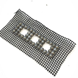 May include: A black mesh fabric with a geometric design made of silver-colored, rounded studs. The studs are arranged in a rectangular pattern with three open squares. The mesh is on a white background.