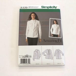 May include: A Simplicity sewing pattern for a women's blouse. The pattern includes three different views: a classic button-up blouse, a blouse with a ruffle detail, and a blouse with a Peter Pan collar. The pattern is labelled "Amazing Fit" and includes instructions for sizes XS-XL.