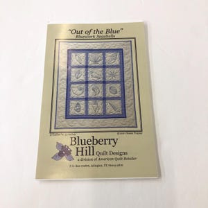 May include: A quilting pattern titled "Out of the Blue" featuring a bluework seashell design. The pattern is for a quilt measuring 27 inches by 33 inches. The pattern is from Blueberry Hill Quilt Designs, a division of American Quilt Retailer.