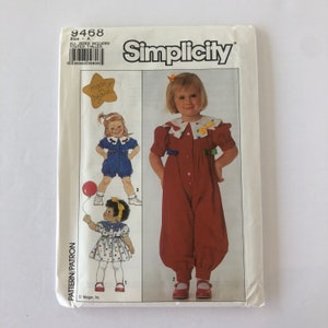 Puede incluir: Patrón de costura Simplicity número 9468 para un mono para niños. El patrón incluye tres estilos diferentes: un mono rojo con cuello blanco y lazo, un mono azul con cuello blanco y lazo y un vestido blanco con cuello azul y lazo. El patrón es para las tallas A, que incluye todas las tallas.
