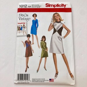 May include: Simplicity sewing pattern number 1012 AA for 1960s vintage dresses. The pattern includes four different dress styles, including a white dress with black geometric shapes, a blue dress, a brown dress with a blue and white geometric pattern, and a green dress. The pattern is designed and printed in the USA.