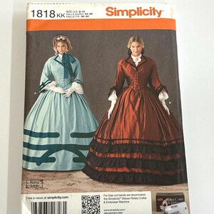 May include: A Simplicity sewing pattern envelope 1818 featuring two historical-style dresses. One dress is light blue with dark blue trim and a bonnet, while the other is a rust-coloured gown with black ruffled tiers and long sleeves.