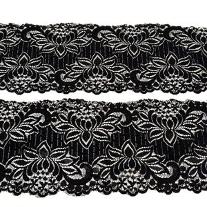Puede incluir: Dos tiras de encaje negro con un diseño floral. El encaje presenta un patrón repetido de flores y hojas estilizadas en blanco sobre un fondo negro. Los bordes son festoneados.