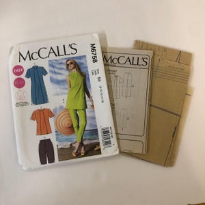 Può includere: Modello di cucito McCall's per una tuta e pantaloni da donna. Il modello è per le taglie 8-10-12-14-16. Il modello è mostrato su una modella che indossa una tuta verde e una donna che indossa un vestito blu e una maglia arancione. Il modello include istruzioni e requisiti di tessuto.