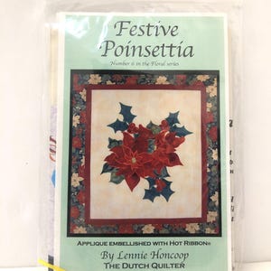 May include: A package featuring a quilt pattern titled "Festive Poinsettia." The design showcases red poinsettias with green leaves, framed by a floral border. The text reads "Applique Embellished with Hot Ribbon" and "By Lennie Honcoop, The Dutch Quilter."