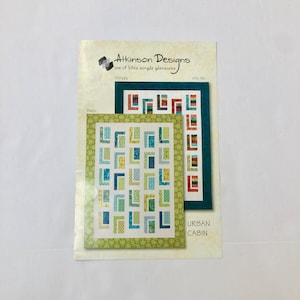 May include: A quilting pattern for a quilt called "Urban Cabin". The pattern includes three different layouts: Strippy, Basic, and Urban Cabin. The quilt is made with a variety of green, blue, and orange fabrics.