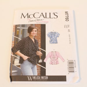May include: A sewing pattern for a women's blouse with a ruffled neckline. The pattern is from McCall's and is for sizes 5-8-10-12-14. The pattern includes a photo of a woman wearing a black and white polka dot blouse.