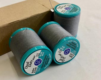 May include: Three spools of gray thread with turquoise labels. The labels read "Dual Duty Plus" and "Button & Craft". Each spool contains 50 yards (45 meters) of thread.