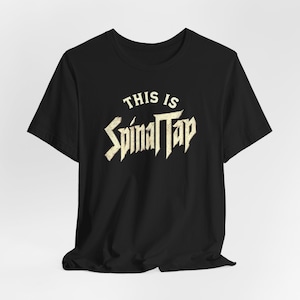 May include: Black t-shirt with a white graphic that says "This is Spinal Tap" in a vintage rock band style font.