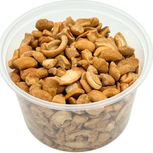 May include: A clear plastic container filled with roasted cashew pieces. The cashews are light brown in color and have a slightly irregular shape.