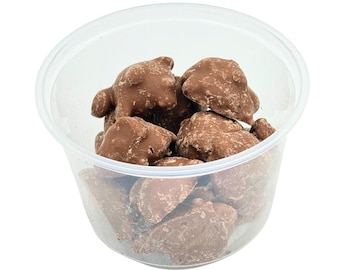 May include: A clear plastic container filled with milk chocolate peanut clusters. The clusters are irregularly shaped and have a rough texture.