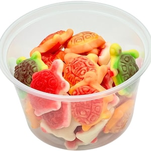 May include: A clear plastic container filled with colorful gummy candies shaped like turtles. The turtles are in shades of red, orange, green, and brown.