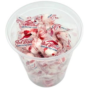 May include: A clear plastic container filled with individually wrapped peppermint candies. The candies are white with red stripes and have the words "Red Bird Handcrafted Candy" printed on the wrappers.