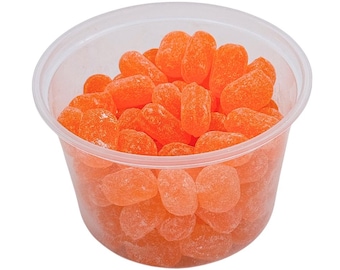 May include: A clear plastic container filled with orange candy. The candy is shaped like small, elongated ovals and has a slightly grainy texture.
